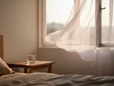 Ein minimalistisches Schlafzimmer am frühen Morgen mit einem Glas Wasser auf einem Nachttisch bei sanftem Tageslicht. - Foto: über boerse-global.de