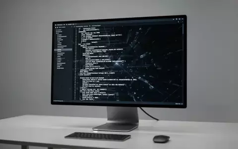 Ein moderner Arbeitsplatz mit einem Monitor, auf dem Codezeilen in einem Terminal-Fenster zu sehen sind. - Foto: über boerse-global.de