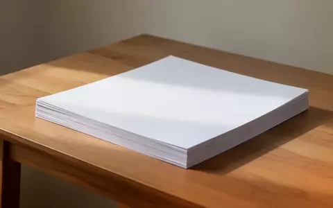 Ein Stapel weißes Papier auf einem schlichten Holztisch in einem hellen, aufgeräumten Büro. - Foto: über boerse-global.de