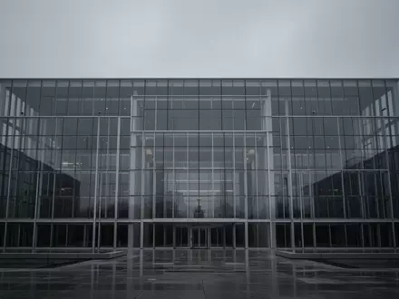 Ein minimalistisches, modernes Regierungsgebäude aus Glas und Stahl unter einem bewölkten Himmel als Symbol für staatliche Aufsicht. - Foto: über boerse-global.de