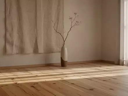 Ein minimalistischer, heller Wohnraum im Japandi-Stil mit natürlichem Holz, sanftem Licht und einer einzelnen Vase. - Foto: über boerse-global.de