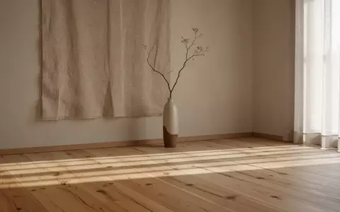 Ein minimalistischer, heller Wohnraum im Japandi-Stil mit natürlichem Holz, sanftem Licht und einer einzelnen Vase. - Foto: über boerse-global.de