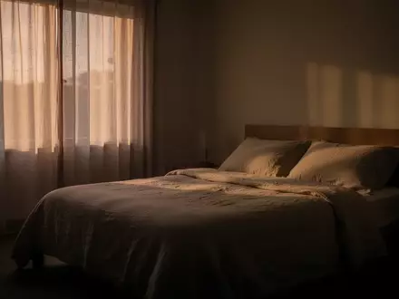 Ein minimalistisch eingerichtetes, ruhiges Schlafzimmer in der Abenddämmerung mit weichem, natürlichem Licht. - Foto: über boerse-global.de