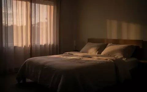 Ein minimalistisch eingerichtetes, ruhiges Schlafzimmer in der Abenddämmerung mit weichem, natürlichem Licht. - Foto: über boerse-global.de