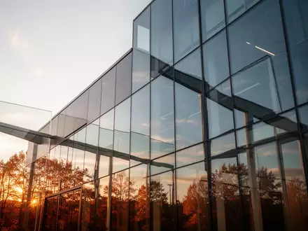 Moderne Glasfassade eines Gebäudes, die den klaren Herbsthimmel reflektiert. - Foto: über boerse-global.de