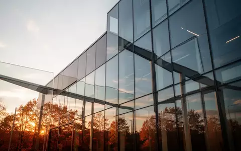 Moderne Glasfassade eines Gebäudes, die den klaren Herbsthimmel reflektiert. - Foto: über boerse-global.de