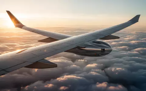 Ein moderner Verkehrsflugzeugflügel über einem Wolkenmeer im goldenen Sonnenlicht. - Foto: über boerse-global.de