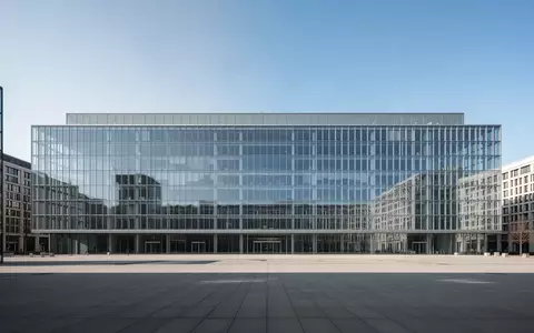 Ein minimalistisches, modernes Verwaltungsgebäude aus Glas und Stahl unter klarem Himmel. - Foto: über boerse-global.de