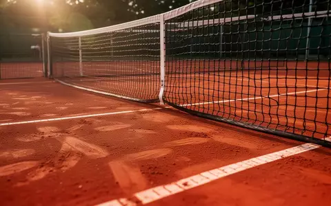 Ein roter Sandplatz mit einem gespannten Tennisnetz im warmen Licht der Nachmittagssonne. - Foto: über boerse-global.de