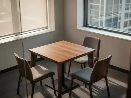 Ein minimalistisch eingerichteter Aufenthaltsraum in einem Büro mit einem Holztisch und Stühlen bei Tageslicht. - Foto: über boerse-global.de