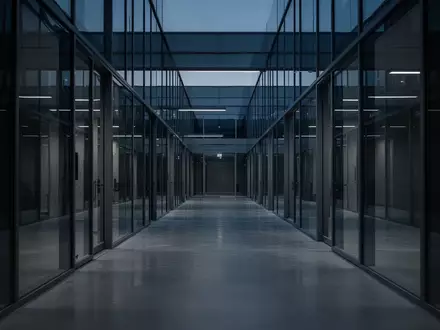 Ein leerer, modern gestalteter Büroflur in kühlem Dämmerlicht mit Fokus auf architektonische Linien. - Foto: über boerse-global.de