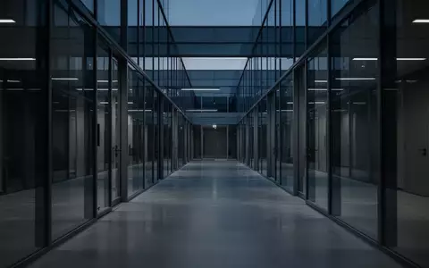 Ein leerer, modern gestalteter Büroflur in kühlem Dämmerlicht mit Fokus auf architektonische Linien. - Foto: über boerse-global.de