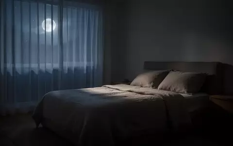 Ein minimalistisch eingerichtetes Schlafzimmer bei Nacht mit sanftem Mondlicht, das durch die Vorhänge fällt. - Foto: über boerse-global.de