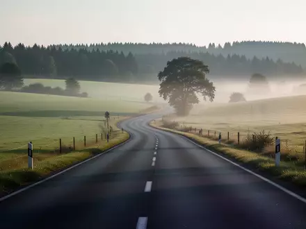 Eine leere, kurvige Landstraße in einer ländlichen Region bei Morgendämmerung. - Foto: über boerse-global.de