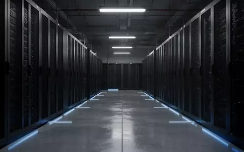 Ein dunkler, moderner Serverraum mit schlichten, unbeschrifteten Serverschränken in einer industriellen Umgebung. - Foto: über boerse-global.de