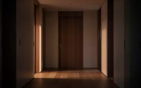 Eine menschenleere, modern gestaltete Wohnungstür in einem schattigen Flur bei Dämmerung. - Foto: über boerse-global.de