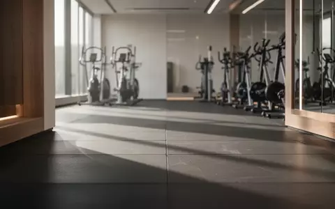Ein minimalistischer, heller Fitnessraum mit hochwertigem Bodenbelag und Sportgeräten im Hintergrund. - Foto: über boerse-global.de