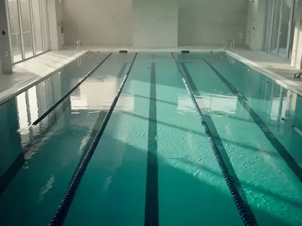 Ein ruhiges Schwimmbecken in einem Hallenbad mit klarem, türkisfarbenem Wasser bei natürlichem Lichteinfall. - Foto: über boerse-global.de