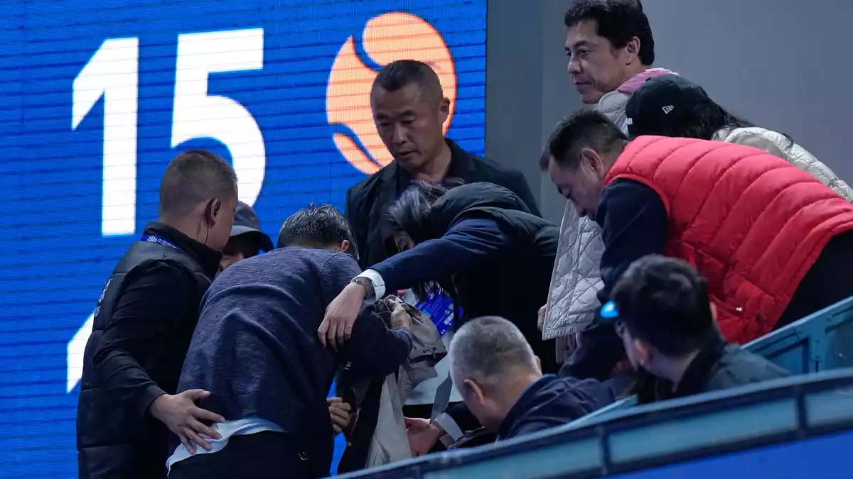 Helfer kümmern sich um einen Mann, der von einem Ball verletzt wurde, den der Russe Medwedew in die Zuschauerränge geschlagen hatte. - Bild: Andy Wong/AP/dpa