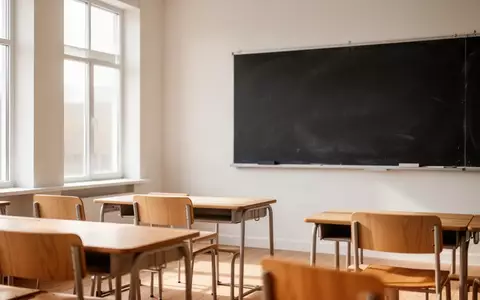 Ein leerer, sonnendurchfluteter Klassenraum mit modernen Holztischen und einer leeren Tafel. - Foto: über boerse-global.de