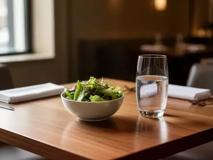 Ein minimalistisch gedeckter Tisch in einem Restaurant mit einer kleinen Schale Salat und einem Glas Wasser. - Foto: über boerse-global.de