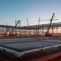 Eine Baustelle für eine neue Industrieanlage bei Dämmerung mit Erdarbeiten und Stahlkonstruktionen. - Foto: über boerse-global.de