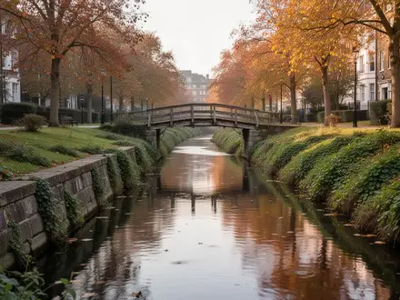 Ein ruhiger Stadtkanal mit einer kleinen Fußgängerbrücke und begrünten Uferbereichen im Spätsommer. - Foto: über boerse-global.de
