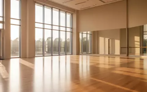 Ein heller, leerer Tanzsaal mit poliertem Holzboden und groĂen Fenstern, durch die natĂŒrliches Tageslicht einfĂ€llt. - Foto: ĂŒber boerse-global.de