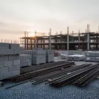 Baustelle mit ordentlich aufgeschichteten Baumaterialien und einem Rohbau im Hintergrund bei Tagesanbruch. - Foto: über boerse-global.de