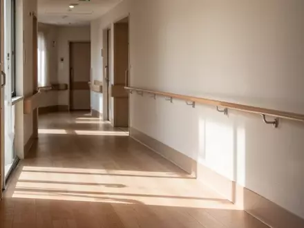 Ein heller, minimalistischer Flur in einer Senioreneinrichtung mit einem barrierefreien Handlauf an der Wand. - Foto: über boerse-global.de