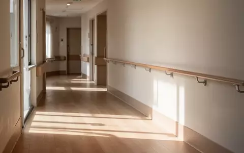 Ein heller, minimalistischer Flur in einer Senioreneinrichtung mit einem barrierefreien Handlauf an der Wand. - Foto: über boerse-global.de