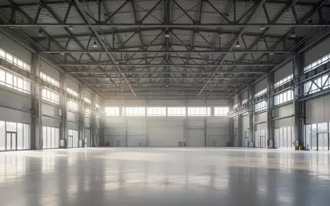 Weite, leere Industriehalle mit hohen Fenstern und einfallendem Tageslicht als Symbol für unternehmerisches Wachstum. - Foto: über boerse-global.de