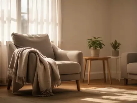 Ein sonnendurchflutetes Wohnzimmer mit einem gemütlichen Sessel und einer Wolldecke in einer ruhigen, privaten Wohnumgebung. - Foto: über boerse-global.de
