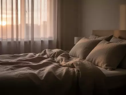 Ein ungemachtes Bett in einem ruhig beleuchteten Schlafzimmer am frühen Morgen, das eine Atmosphäre der Ruhe vermittelt. - Foto: über boerse-global.de