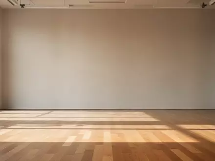 Ein minimalistischer, lichtdurchfluteter Fitnessraum mit einem sauberen Holzboden und einer leeren, neutralen Wand. - Foto: über boerse-global.de