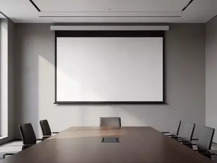 Ein heller, minimalistischer Konferenzraum mit einer leeren Projektionsfläche vor einer grauen Wand. - Foto: über boerse-global.de
