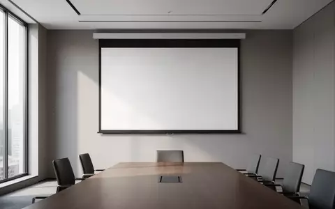 Ein heller, minimalistischer Konferenzraum mit einer leeren Projektionsfläche vor einer grauen Wand. - Foto: über boerse-global.de