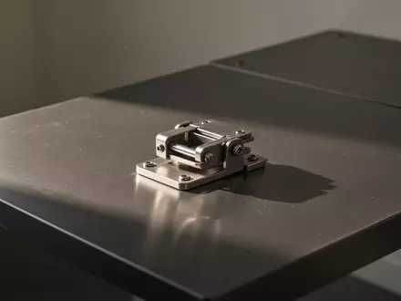 Ein minimalistischer, metallischer Verschlussmechanismus auf einer sauberen, dunklen Arbeitsfläche. - Foto: über boerse-global.de