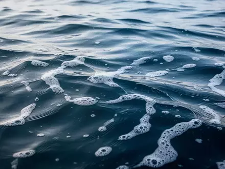 Nahaufnahme von tiefblauem, klarem Ozeanwasser mit sanften Wellen und weißem Schaum bei natürlichem Tageslicht. - Foto: über boerse-global.de
