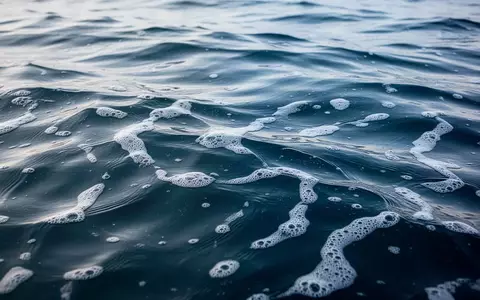Nahaufnahme von tiefblauem, klarem Ozeanwasser mit sanften Wellen und weißem Schaum bei natürlichem Tageslicht. - Foto: über boerse-global.de