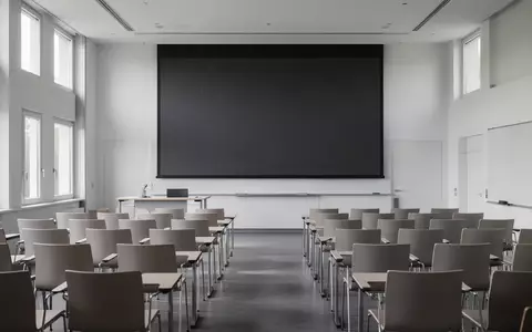 Ein leerer, modern gestalteter medizinischer Hörsaal in München mit Blick auf eine dunkle Projektionsfläche. - Foto: über boerse-global.de