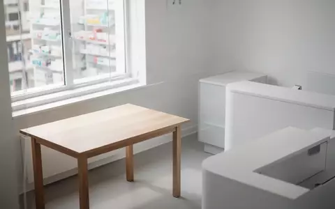Ein heller, minimalistischer Beratungsbereich in einer Apotheke mit einem leeren Holztisch und neutralem Hintergrund. - Foto: über boerse-global.de