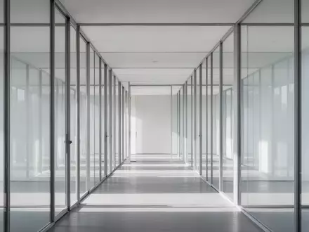 Moderne Glasarchitektur mit klaren Strukturen und Lichtreflexionen in einem leeren, minimalistischen Korridor. - Foto: über boerse-global.de