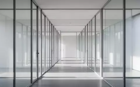 Moderne Glasarchitektur mit klaren Strukturen und Lichtreflexionen in einem leeren, minimalistischen Korridor. - Foto: über boerse-global.de