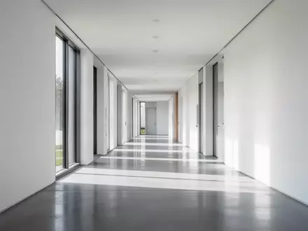 Ein minimalistischer Flur in einem Verwaltungsgebäude mit poliertem Betonboden und hellem Tageslicht. - Foto: über boerse-global.de
