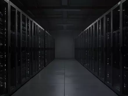 Dunkler, industrieller Serverraum mit leeren, unbeleuchteten Server-Racks in einer minimalistischen Umgebung. - Foto: über boerse-global.de