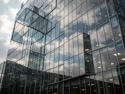 Moderne Glasfassade eines Bürogebäudes bei bewölktem Himmel als Symbol für den Aktienmarkt. - Foto: über boerse-global.de