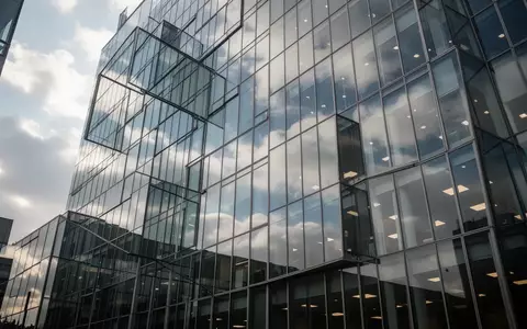Moderne Glasfassade eines Bürogebäudes bei bewölktem Himmel als Symbol für den Aktienmarkt. - Foto: über boerse-global.de