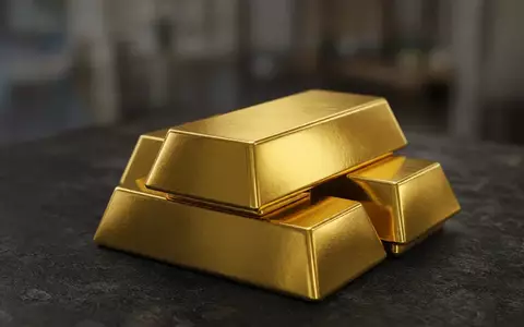 Mehrere glänzende Goldbarren auf einer dunklen, strukturierten Oberfläche in einer professionellen Umgebung. - Foto: über boerse-global.de