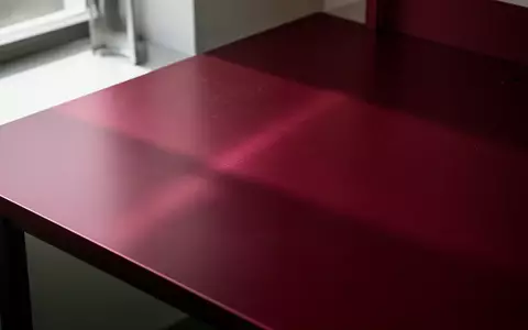 Eine Nahaufnahme einer gebürsteten, dunkelroten Aluminiumoberfläche in einem minimalistischen, industriellen Arbeitsumfeld. - Foto: über boerse-global.de